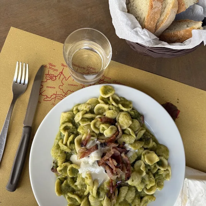 Orecchiette al pesto con guanciale croccante e una cucchiaiata di stracciatella, con il cestino del pane accanto.