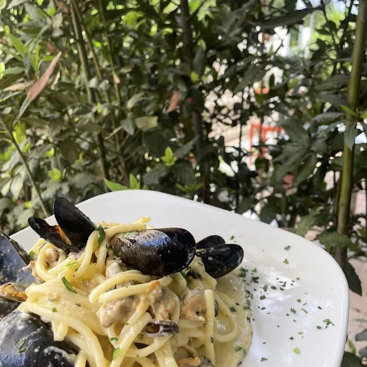 Un piatto di spaghetti con le cozze, servito a un tavolo del giardino.